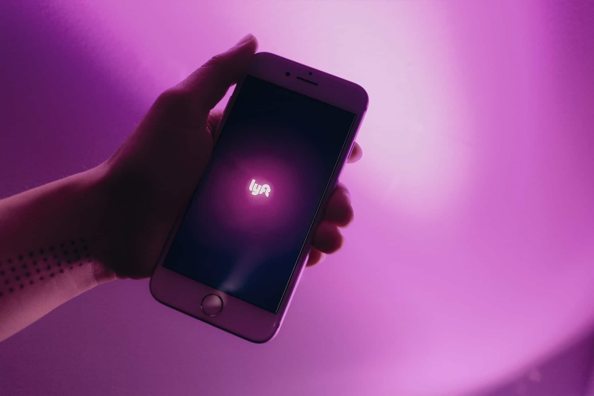 person's hand holding a phone using the Lyft app